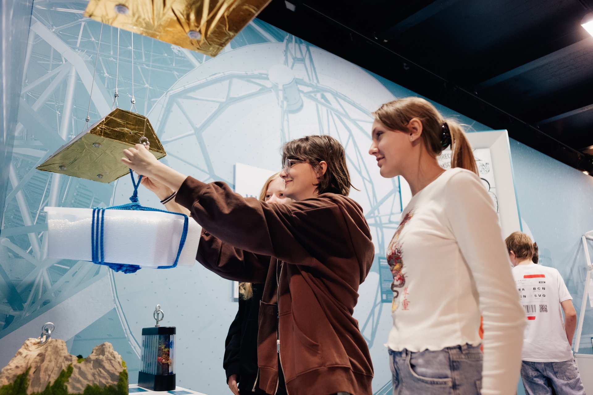 Drei Kinder schauen ein Ausstellungsstück an. 