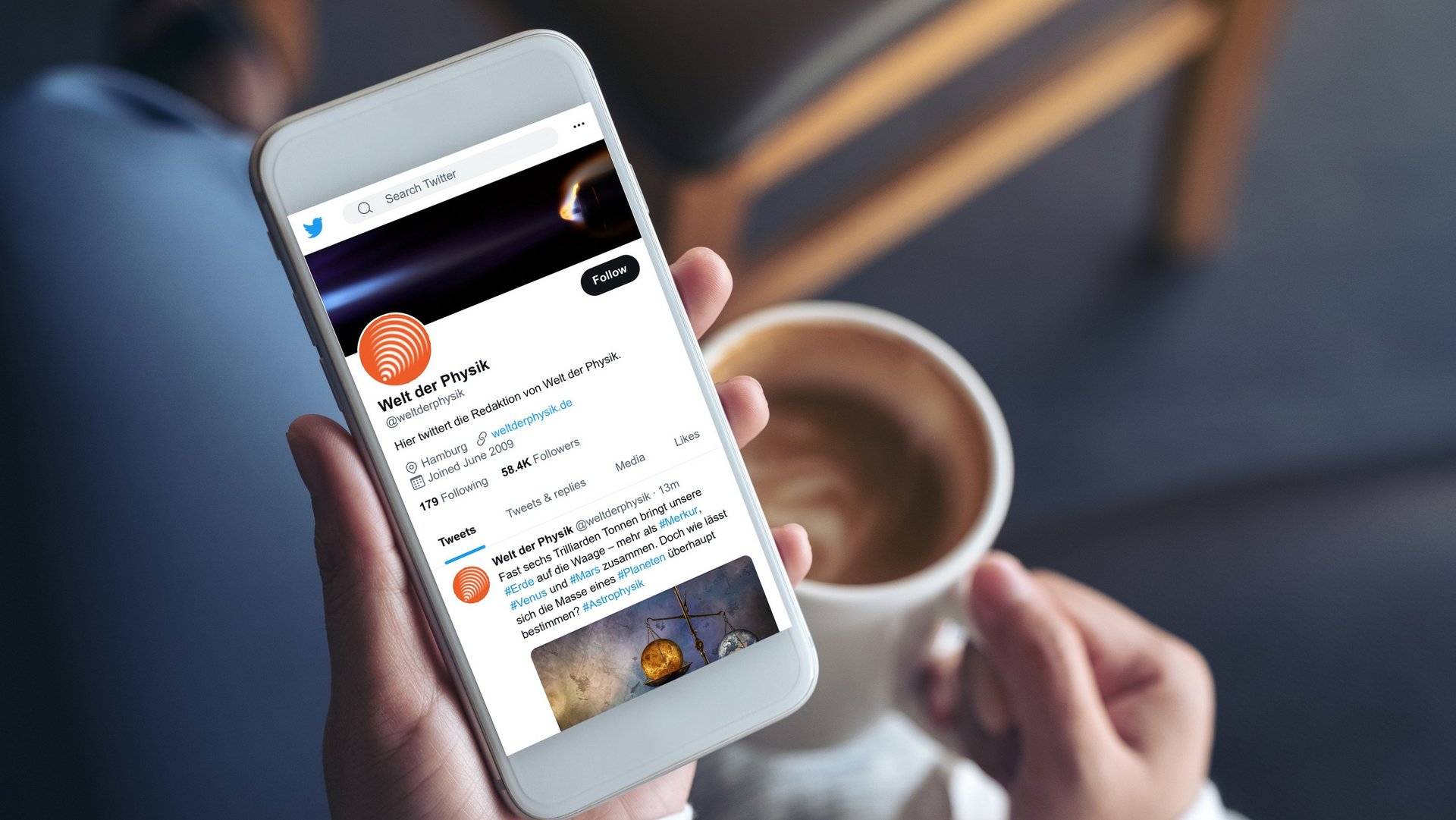 Foto von einer Person, die ein Handy in linker Hand, in rechter Hand einen Kaffee hält