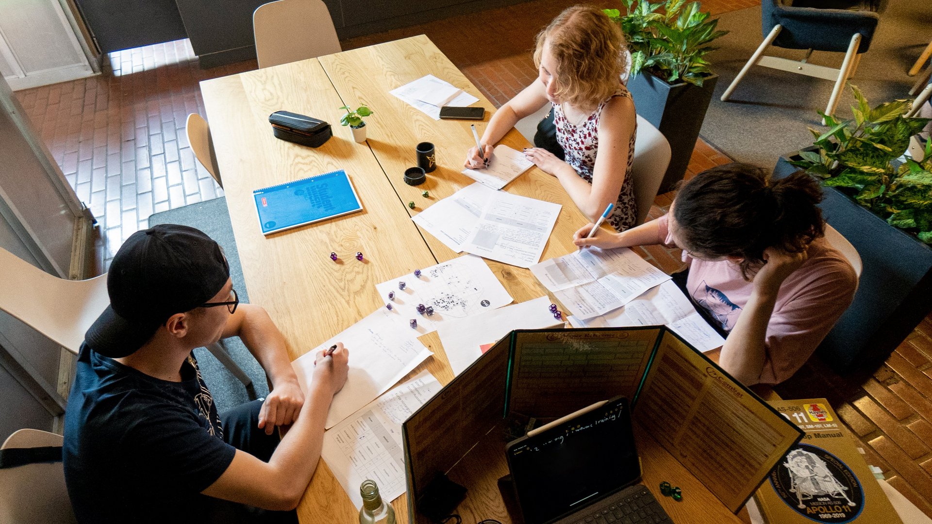 Foto von drei Jugendlichen, die ein Pen & Paper-Rollenspiel spielen. 
