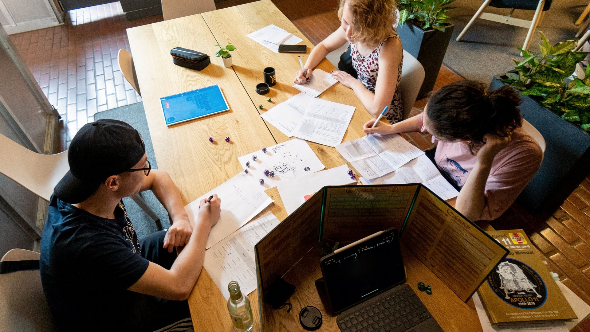 Foto von drei Jugendlichen, die ein Pen & Paper-Rollenspiel spielen. 