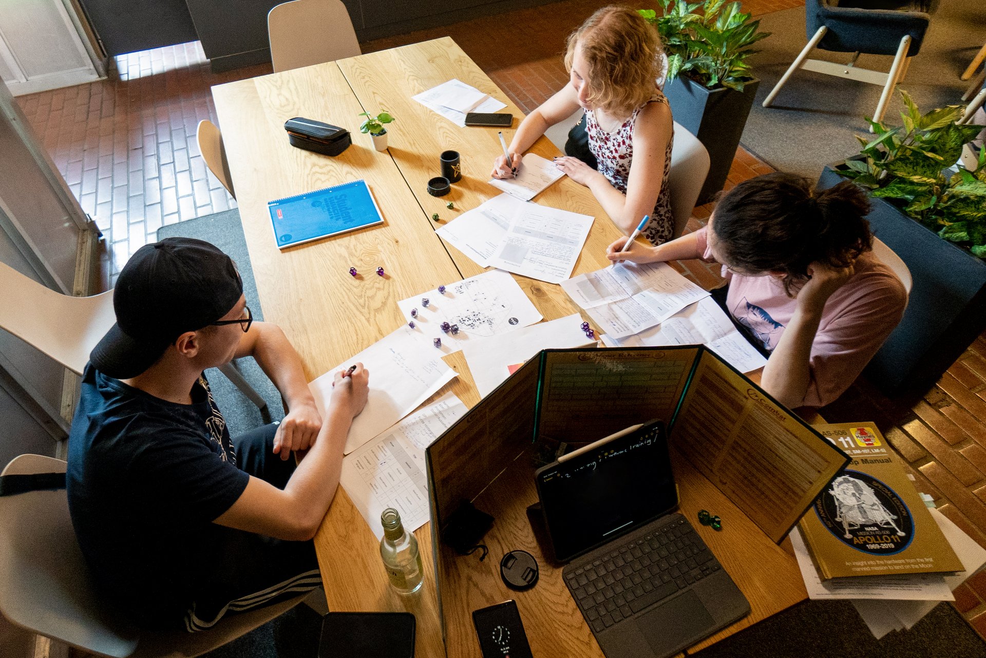 Foto von drei Jugendlichen, die ein Pen & Paper-Rollenspiel spielen. 