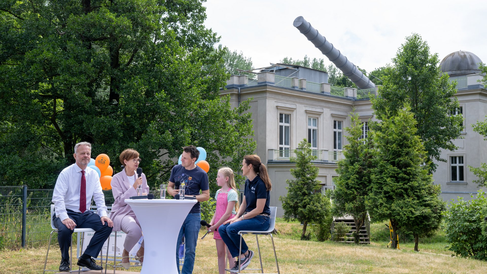 Mehrere Personen an einem Tisch in einem Garten