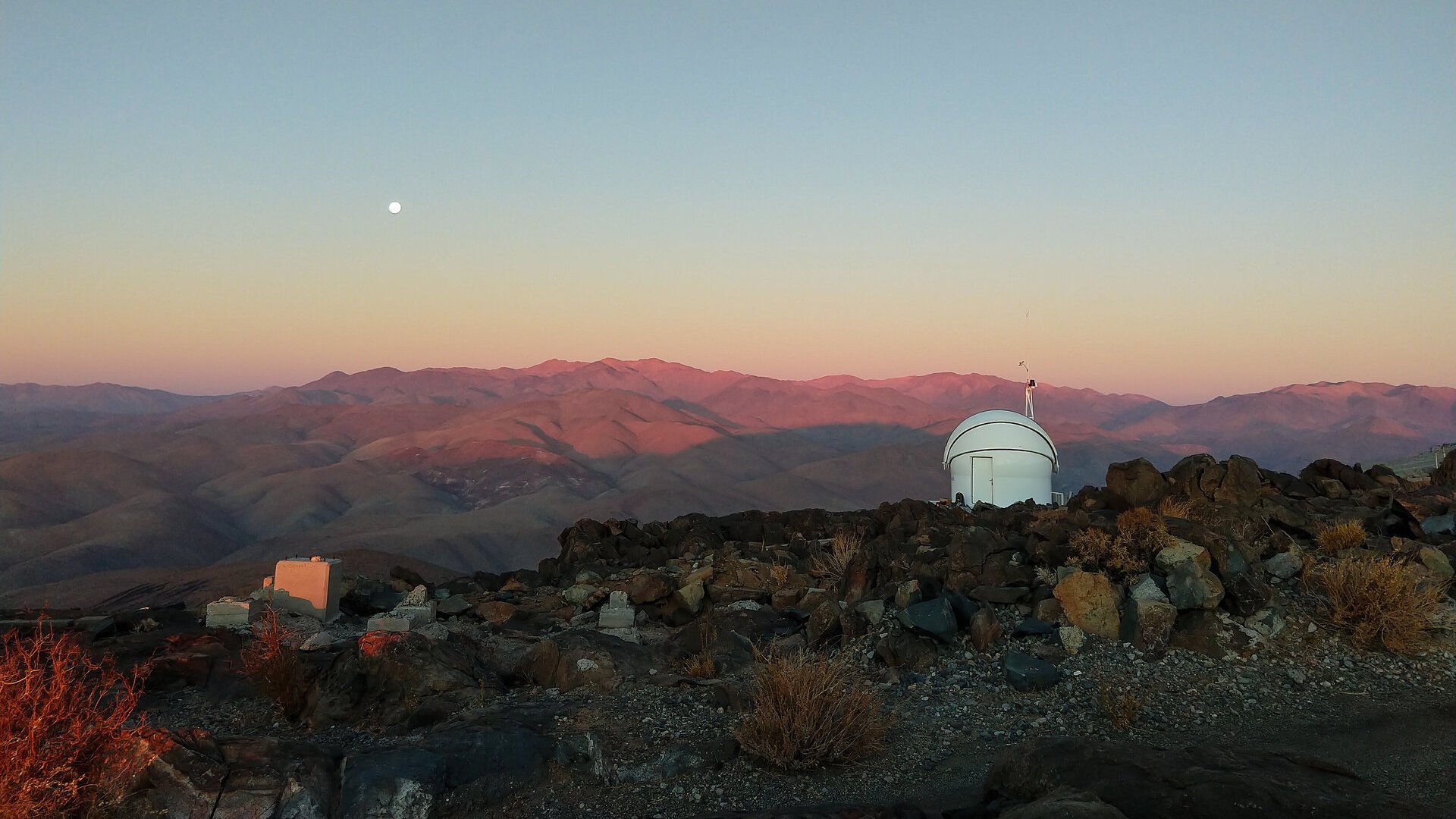 Das Testbed Telescope 2 der ESA am La-Silla-Observatorium der ESO in Chile blickt bei Sonnenuntergang auf die Atacama-Wüste. Links im Bild ist der Mondaufgang zu sehen.