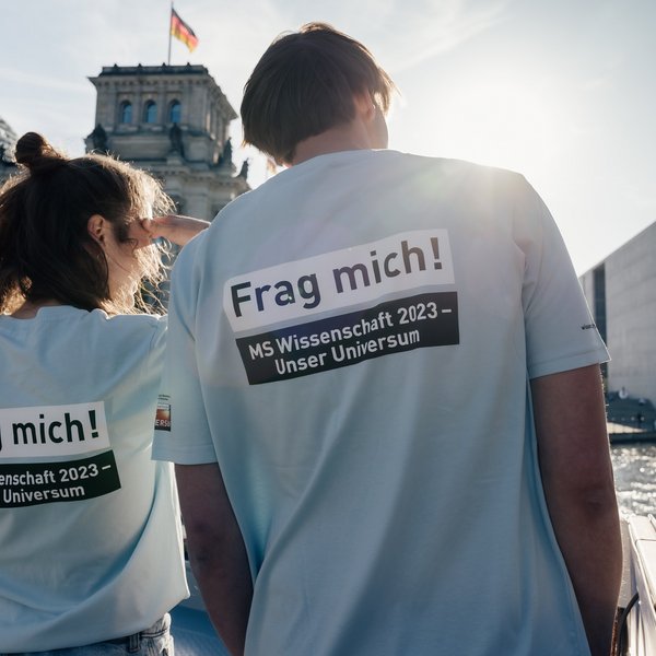 Drei Personen von hinten, Aufdruck auf den "T-Shirts: Frag mich! MS Wissenschaft". 
