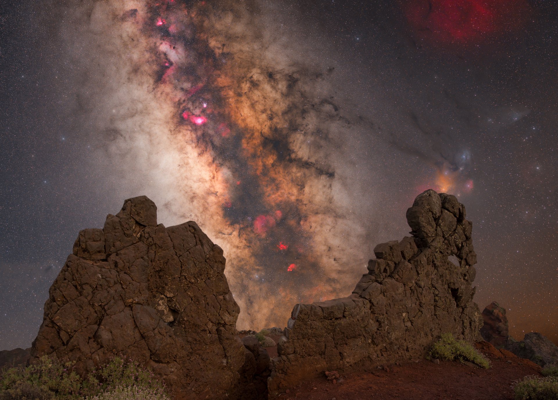 Ein bunter Galaxiestrahl am Himmel, der durch zwei Felsen umrahmt wird