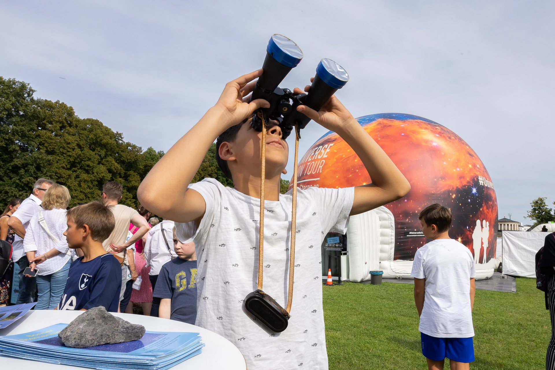 Ein Kind schaut durch ein Fernglas in den Himmel