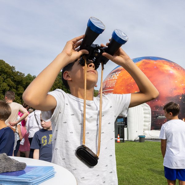 Ein Kind schaut durch ein Fernglas in den Himmel