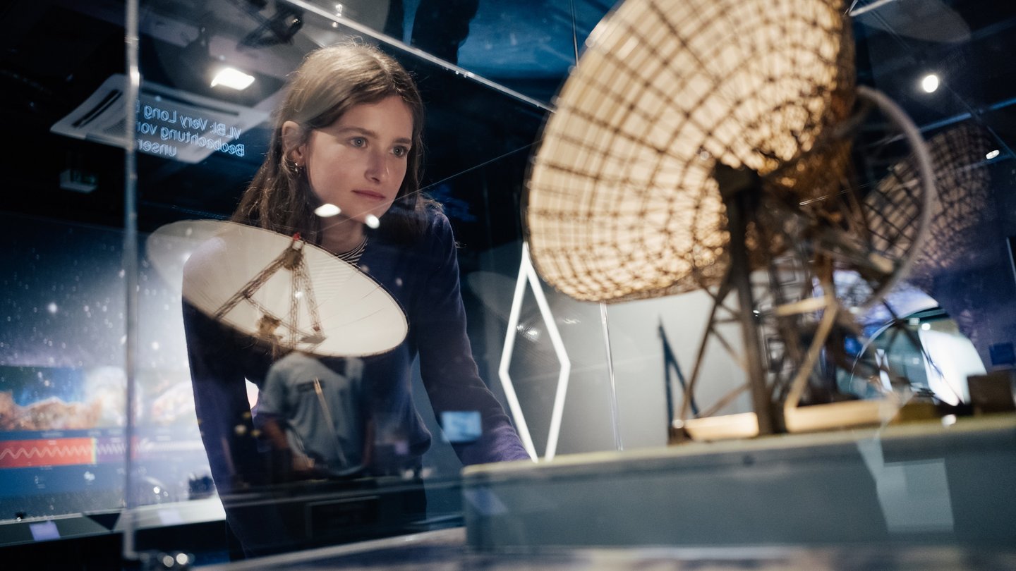 Eine Frau schaut sich ein Modell eines Radioteleskops an. 
