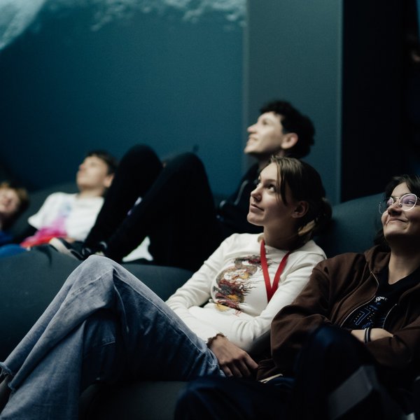 Personengruppe auf einem Sofa, die sich ein Ausstellungsexponat ansehen