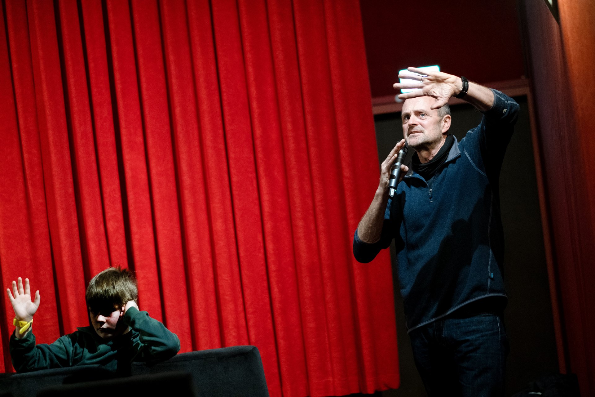 Ein Mann und ein Kind mit einem Mikrofon im Kinosaal.