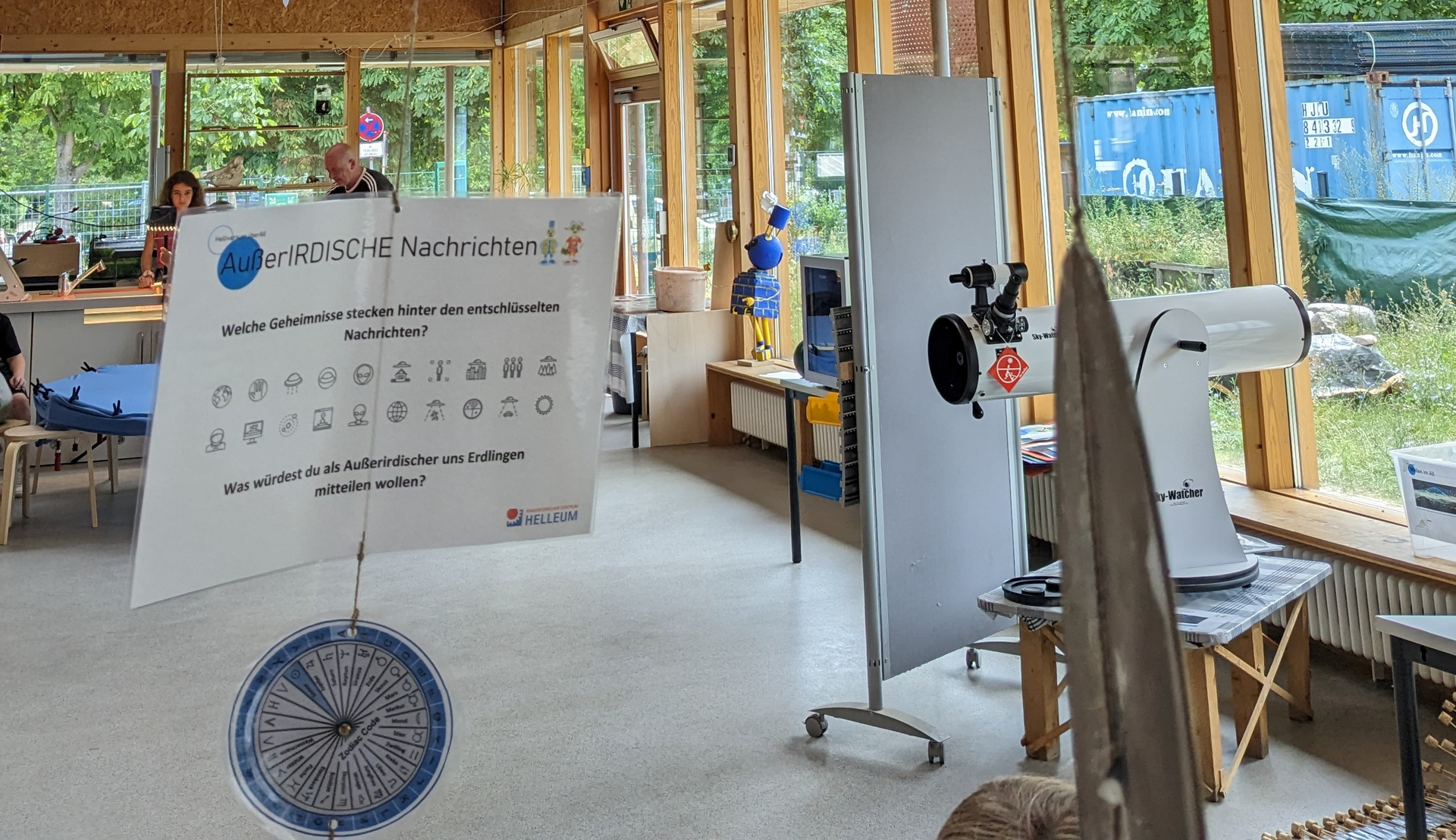 Lichtdurchfluteter Raum mit Stelltafeln und Teleskop 