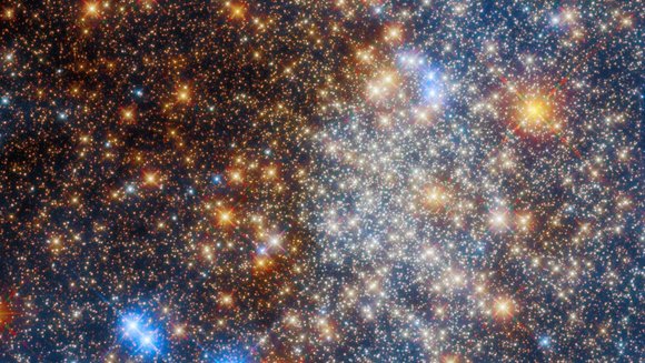 Ansammlung leuchtender orangener und blauer Sterne, zum Zentrum hin heller werdend.