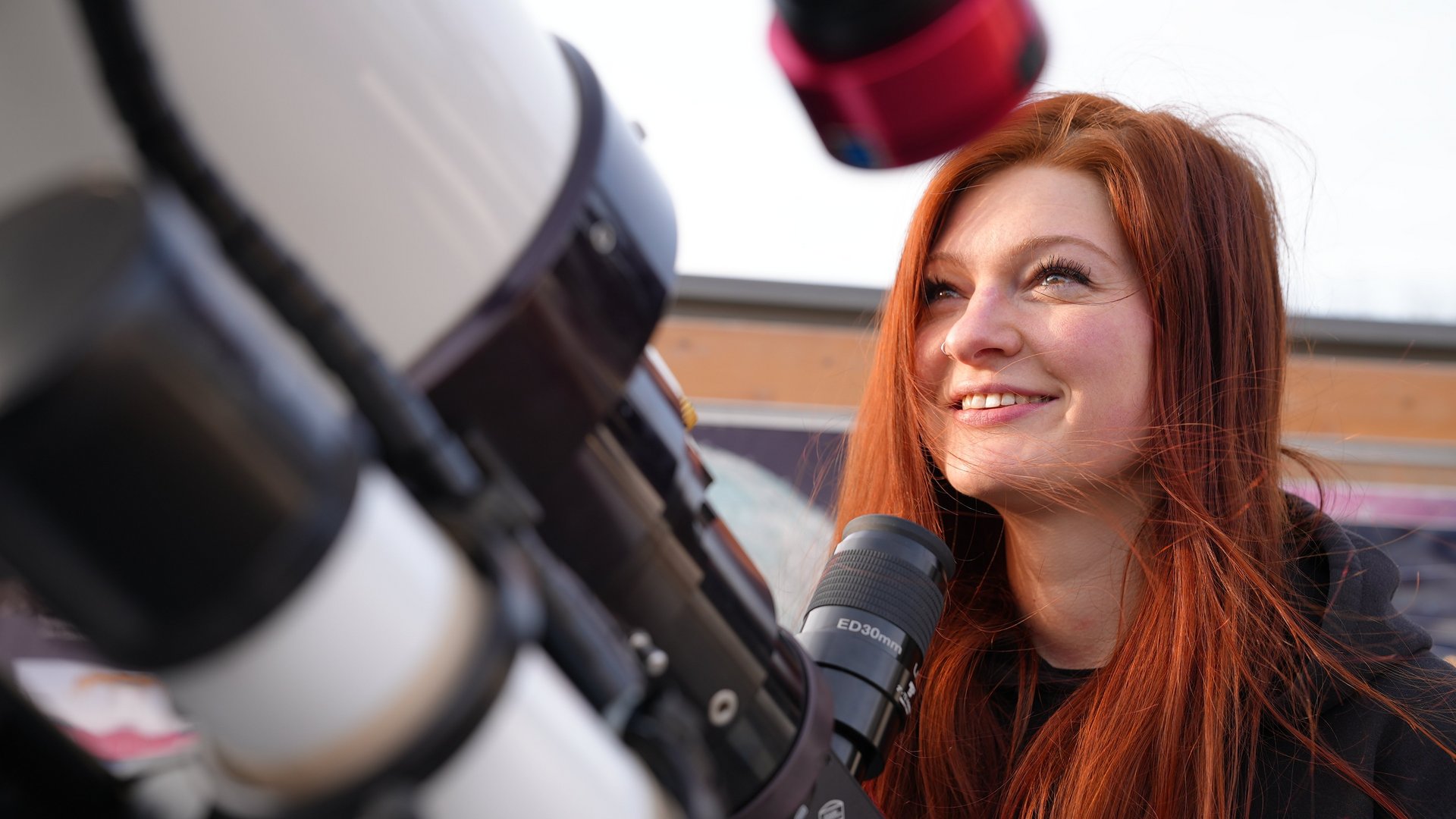 Isabella Graßl vor einem Teleskop.