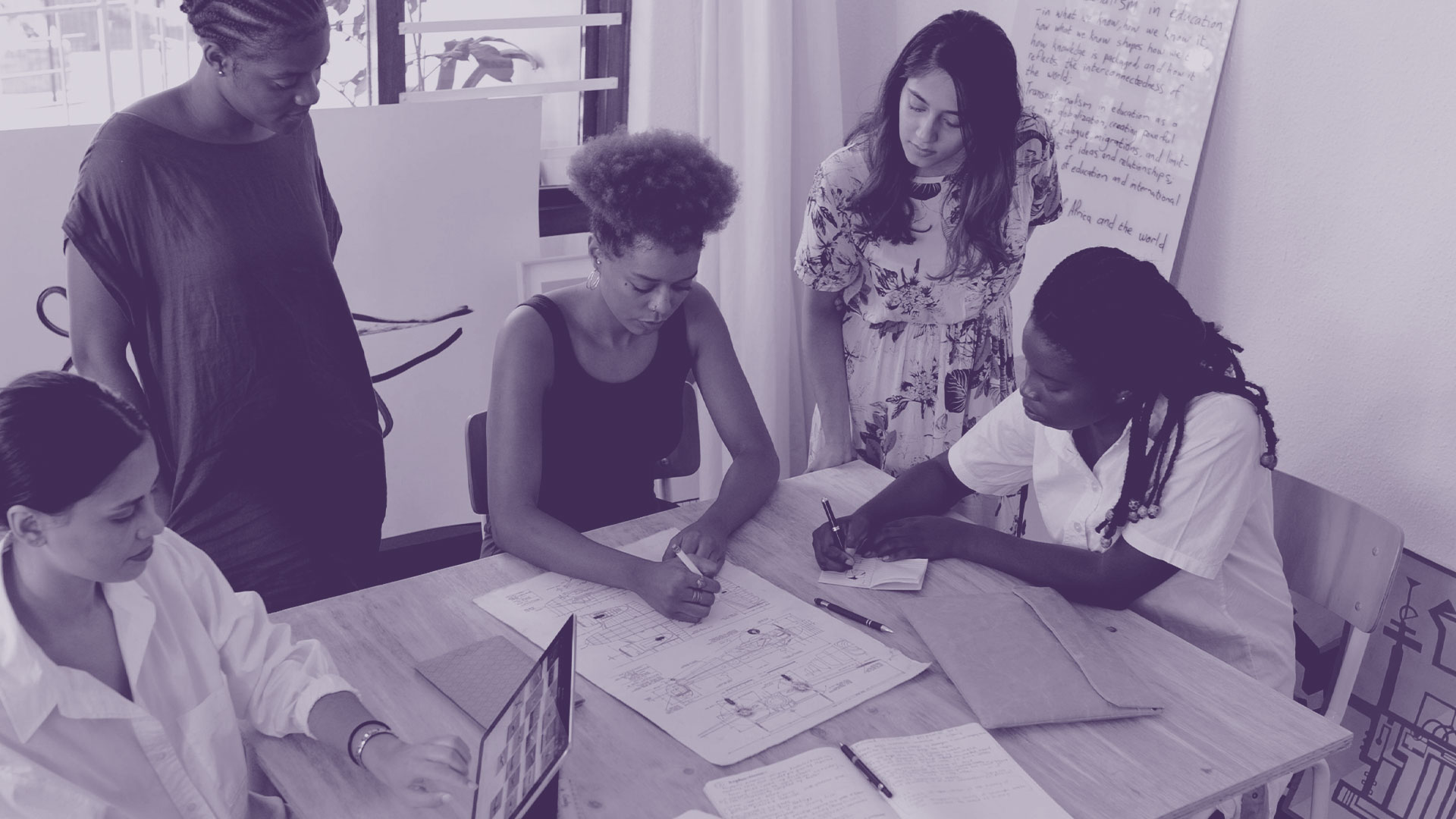 Foto einer Arbeitsgruppe um einen Schreibtisch.