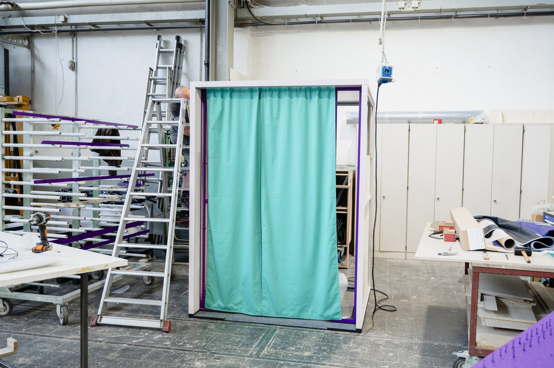 Außenansicht der Erzählbox während des Bauprozesses in der Werkstatt. Das Gerüst trägt einen grünen Vorhang.
