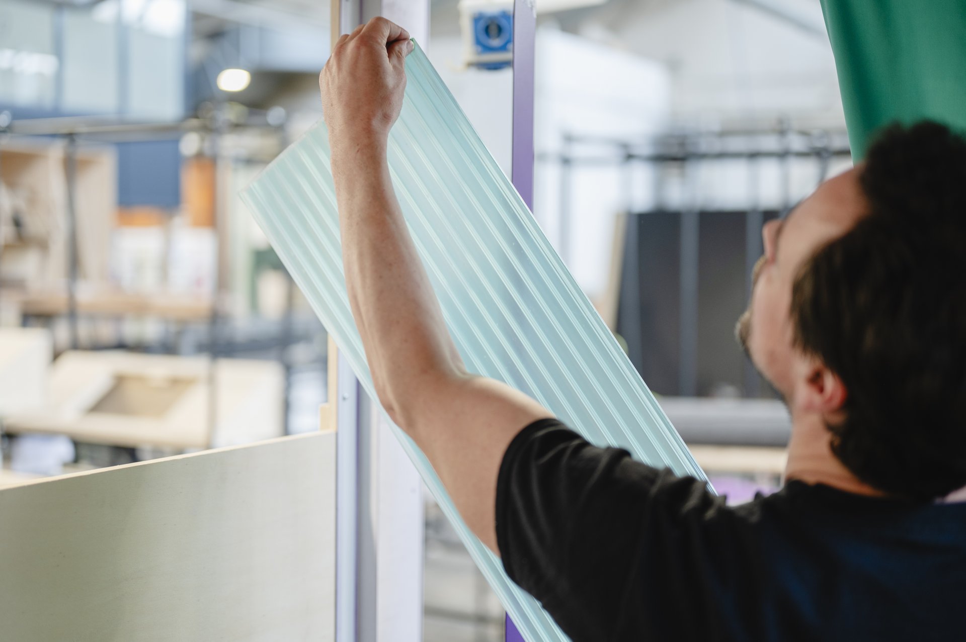 Eine Person hält eine durchsichtige Bahn der Rückwand in den Händen.