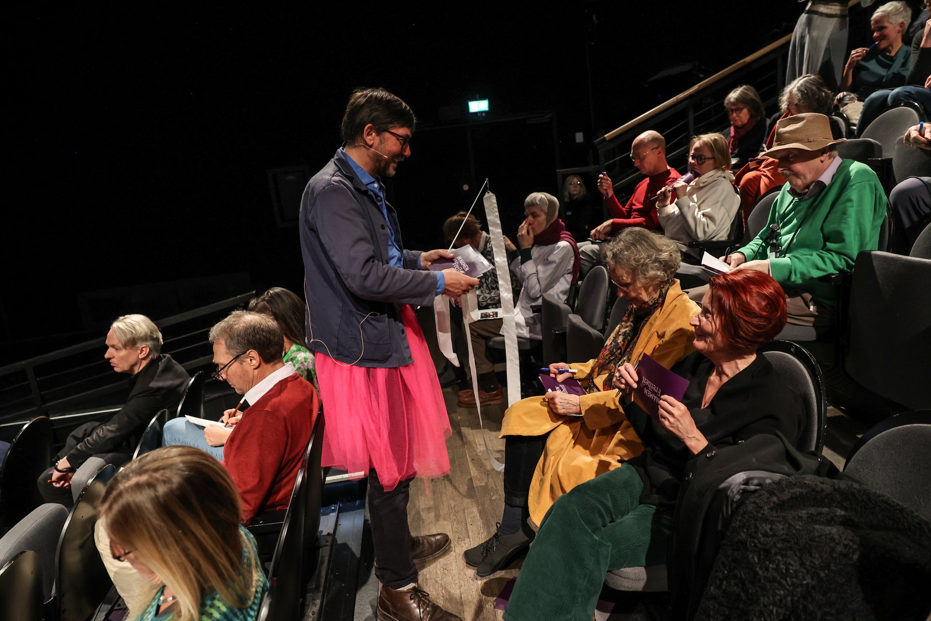 Uwe Gössel als Fee verkleidet verteilt Karten im Publikum.