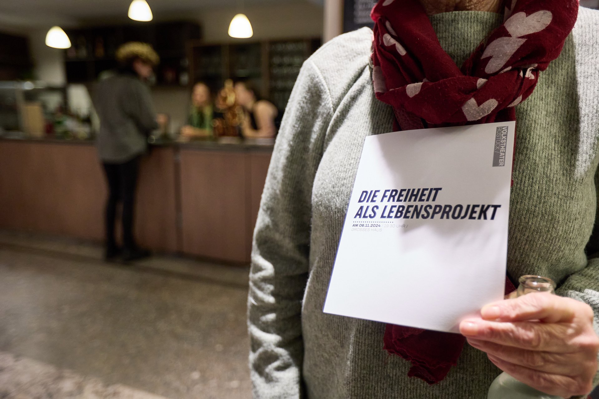 Eine Person hält einen Flyer mit der Aufschrift „Freiheit als lebensprojekt“.