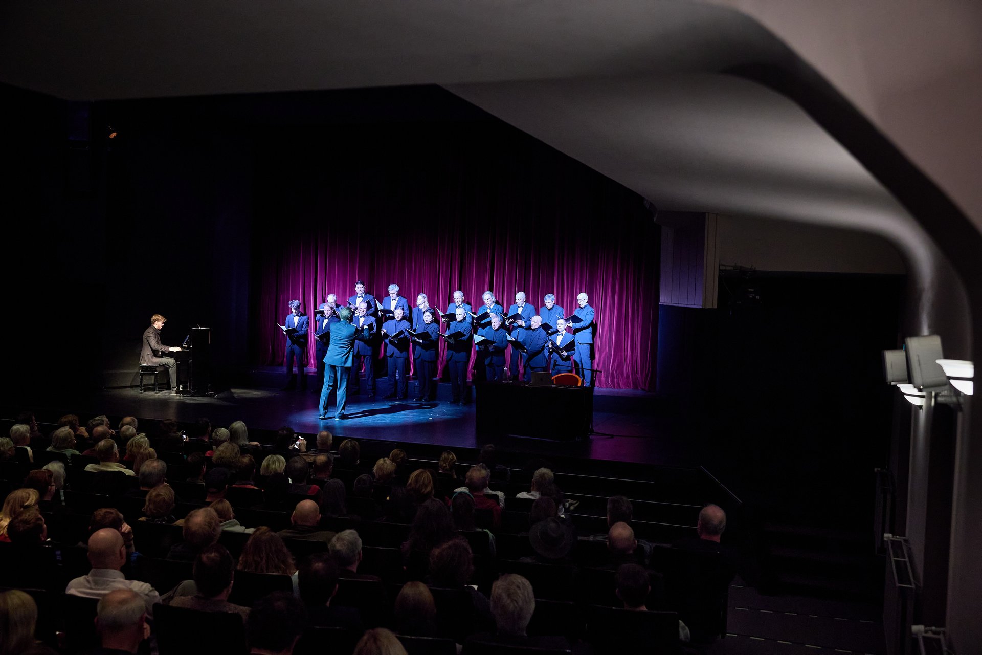 Der Chor singt begleitet vom Klavier auf der Bühne vor Publikum.