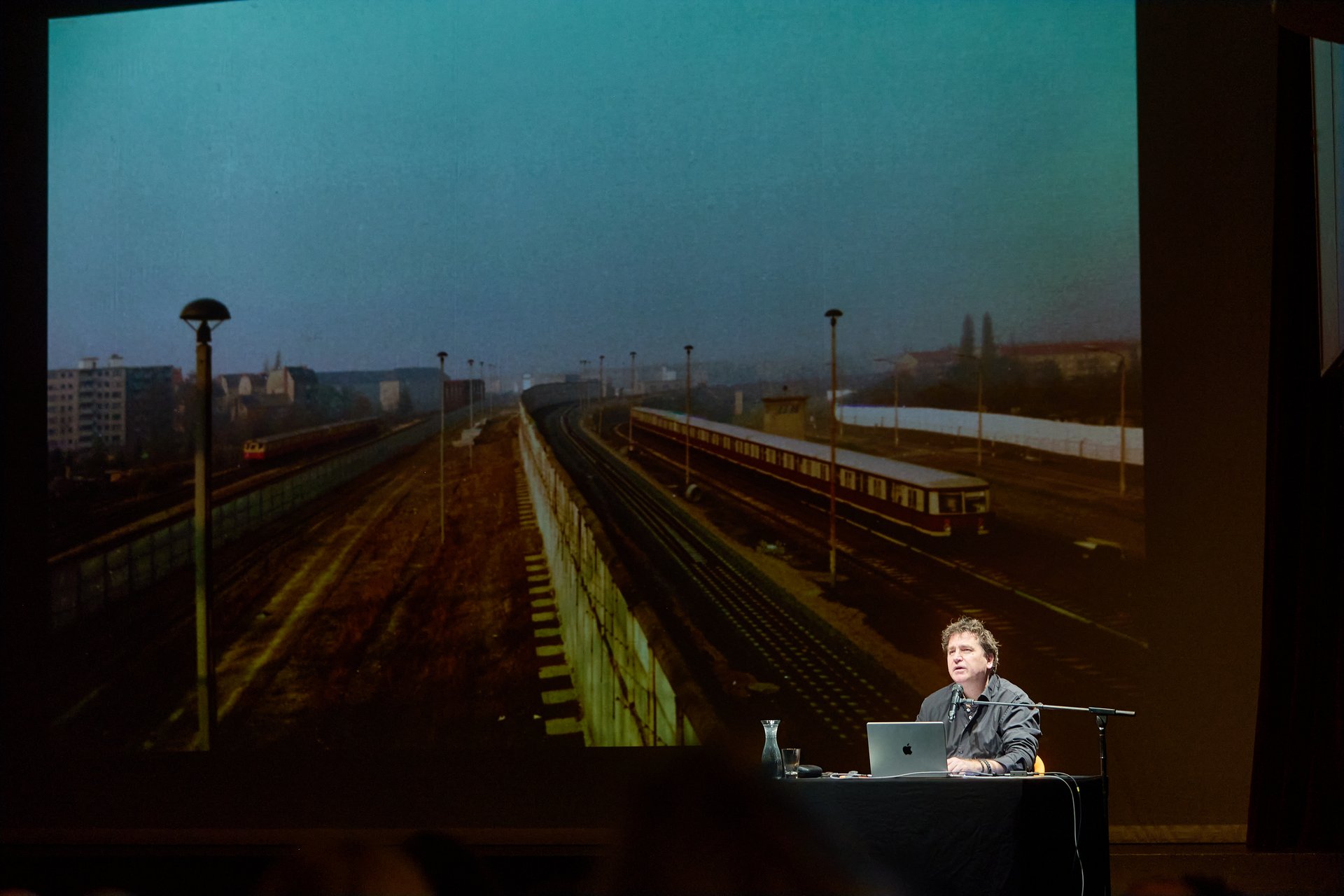 Historiker Ilko-Sascha Kowalczuk sitzt vor der Projektion von Eisenbahnschienen.