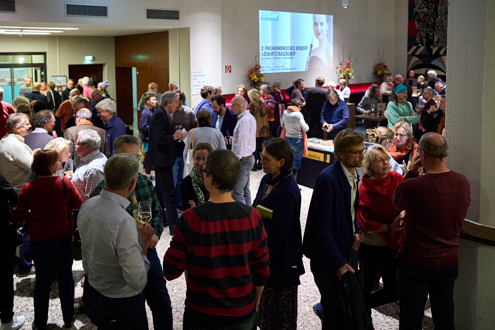 Gäste unterhalten sich im Foyer des Volkstheaters Rostock.