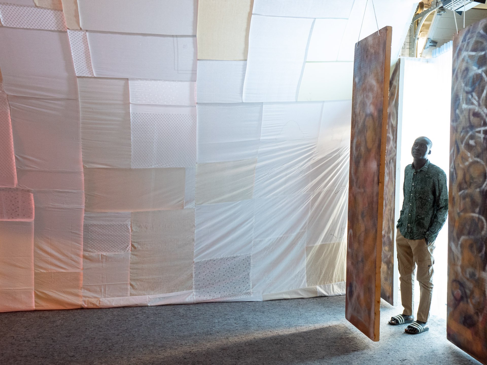 Ein Mann betritt einen Raum mit gespannten Tüchern.