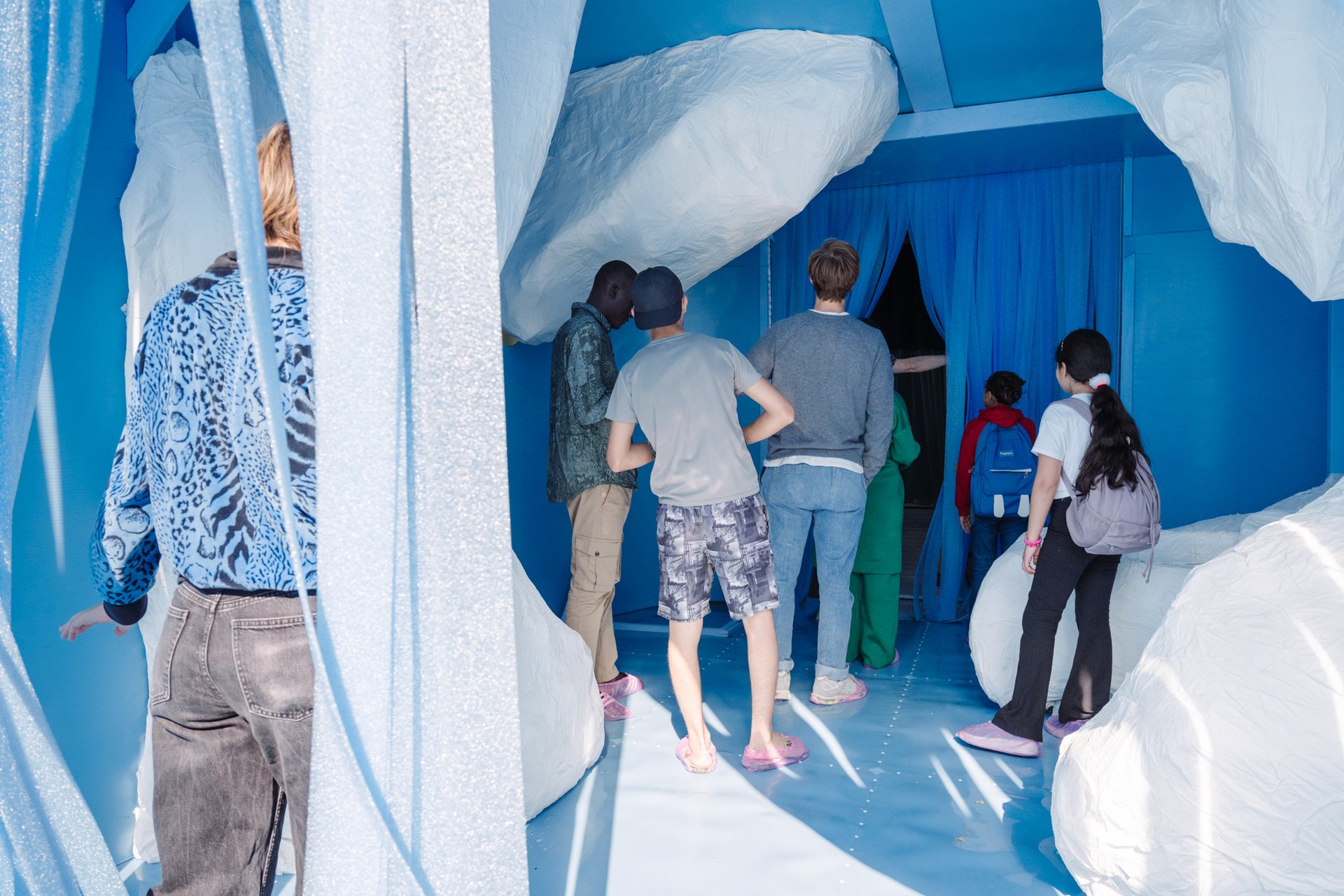 Mehrere Besuchende stehen am Eingang einer Kunstinstallation.