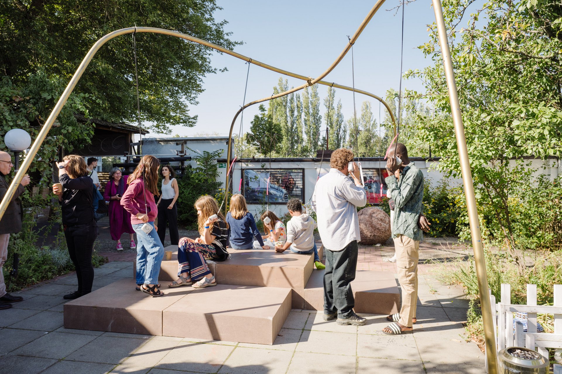 Besuchende hören sich Interviews über kleine, herabhängende Lautsprecher an.