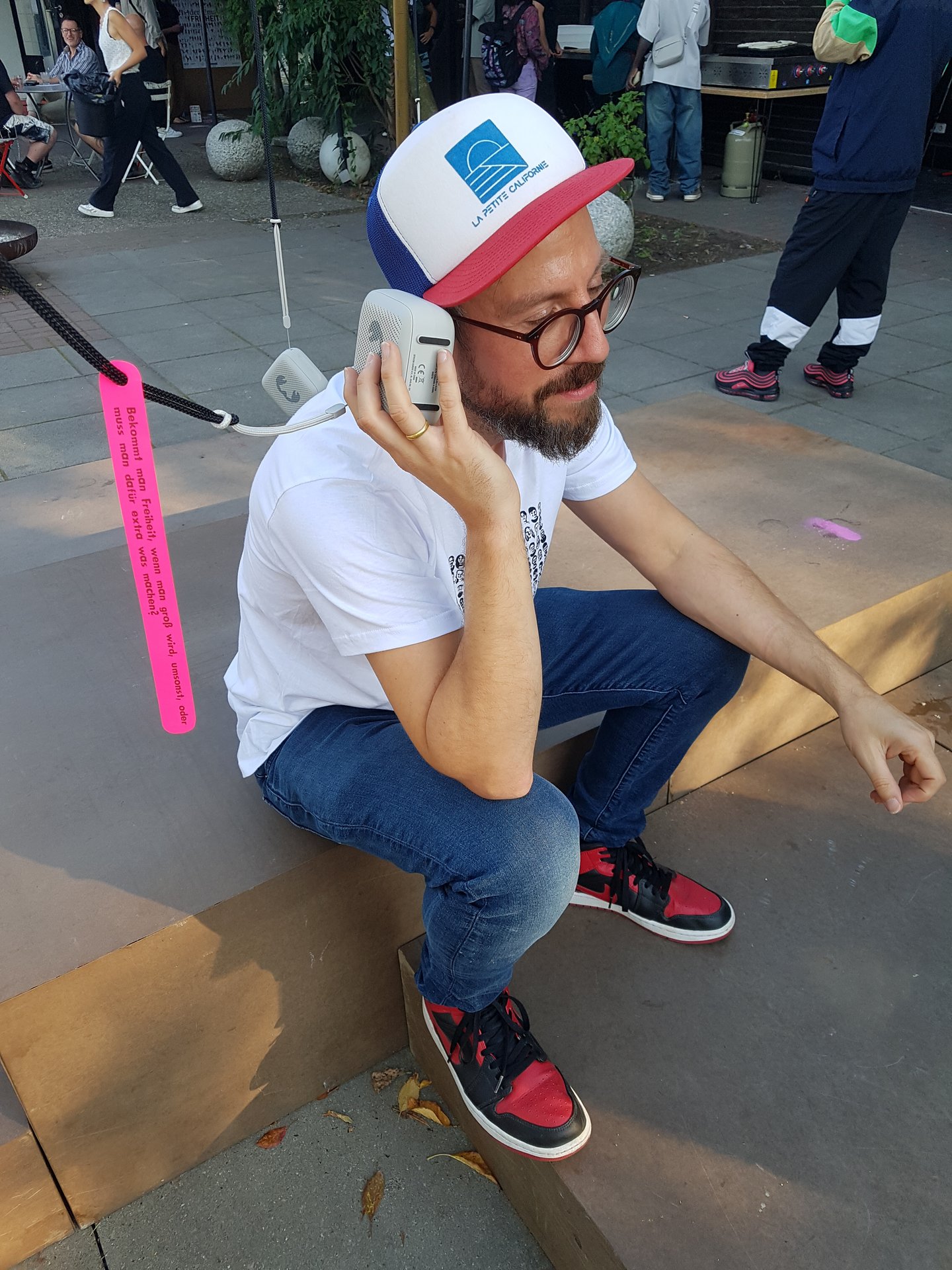 Ein Mann horcht einem Interview durch einen kleinen Lautsprecher.