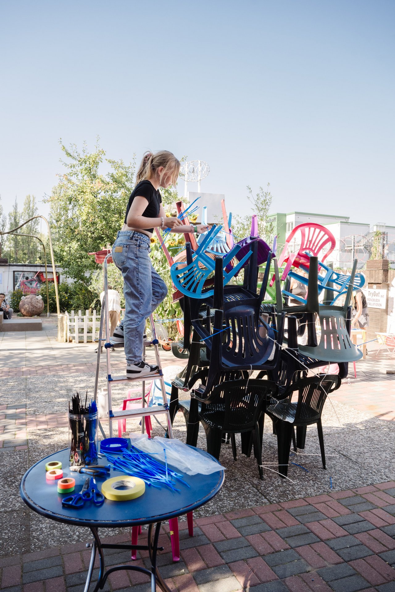 Eine Schülerin baut einen Turm aus Plastikstühlen.