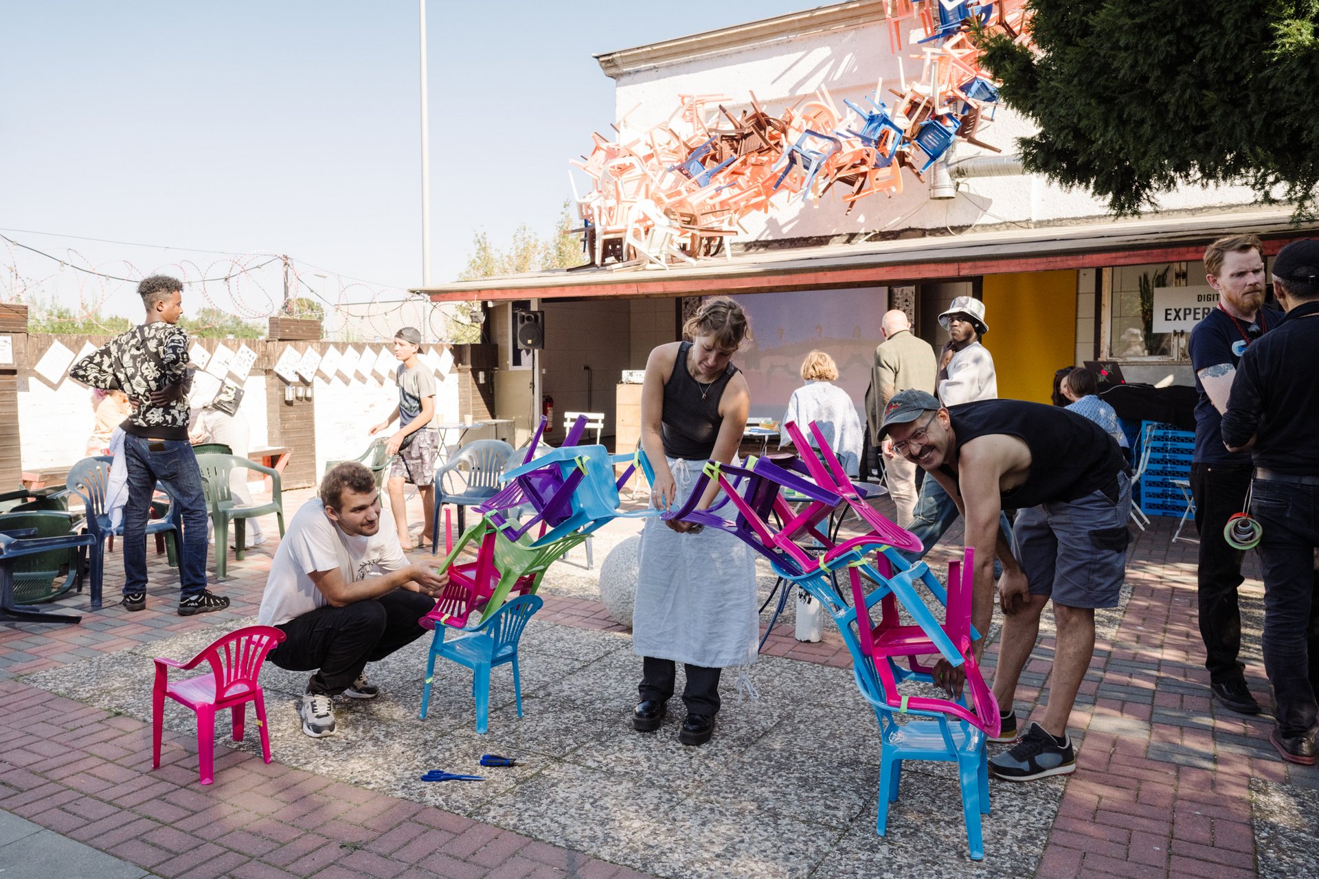 Eine Gruppe Erwachsener baut das Fundament für einen Turm aus Plastikstühlen.
