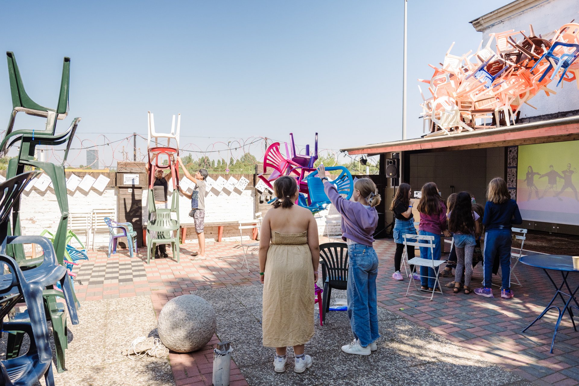 Kinder bauen einen Turm aus Plastikstühlen.