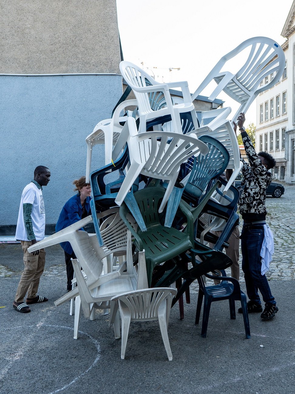 Junge Menschen stapeln Plastikstühle.