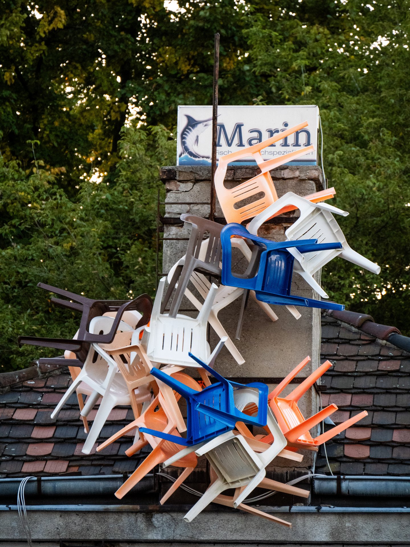 Ein Stapel Plastikstühle auf einem Hausdach.