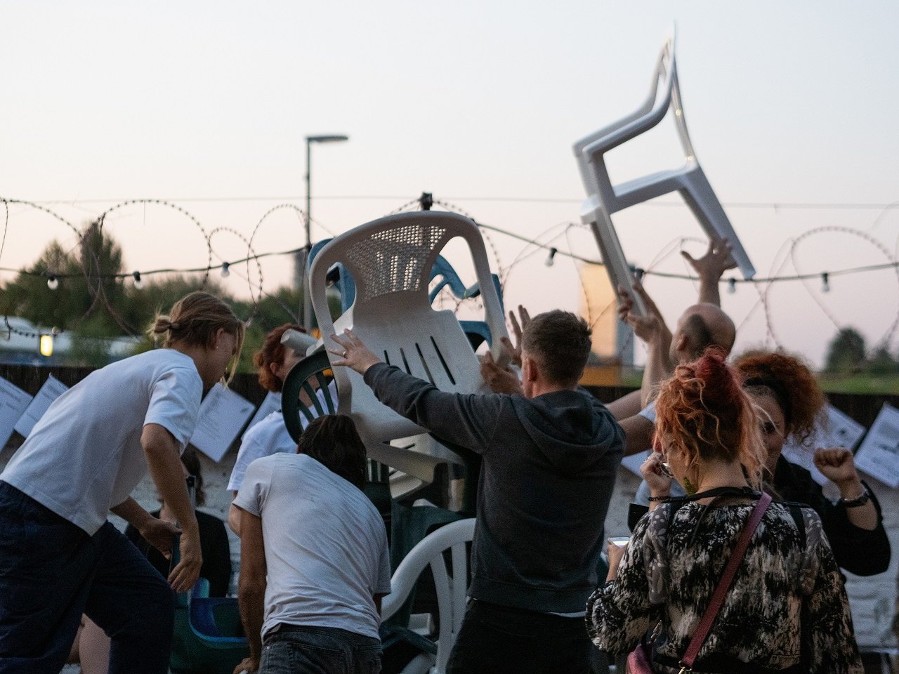 Junge Menschen tanzen mit Plastikstühlen.