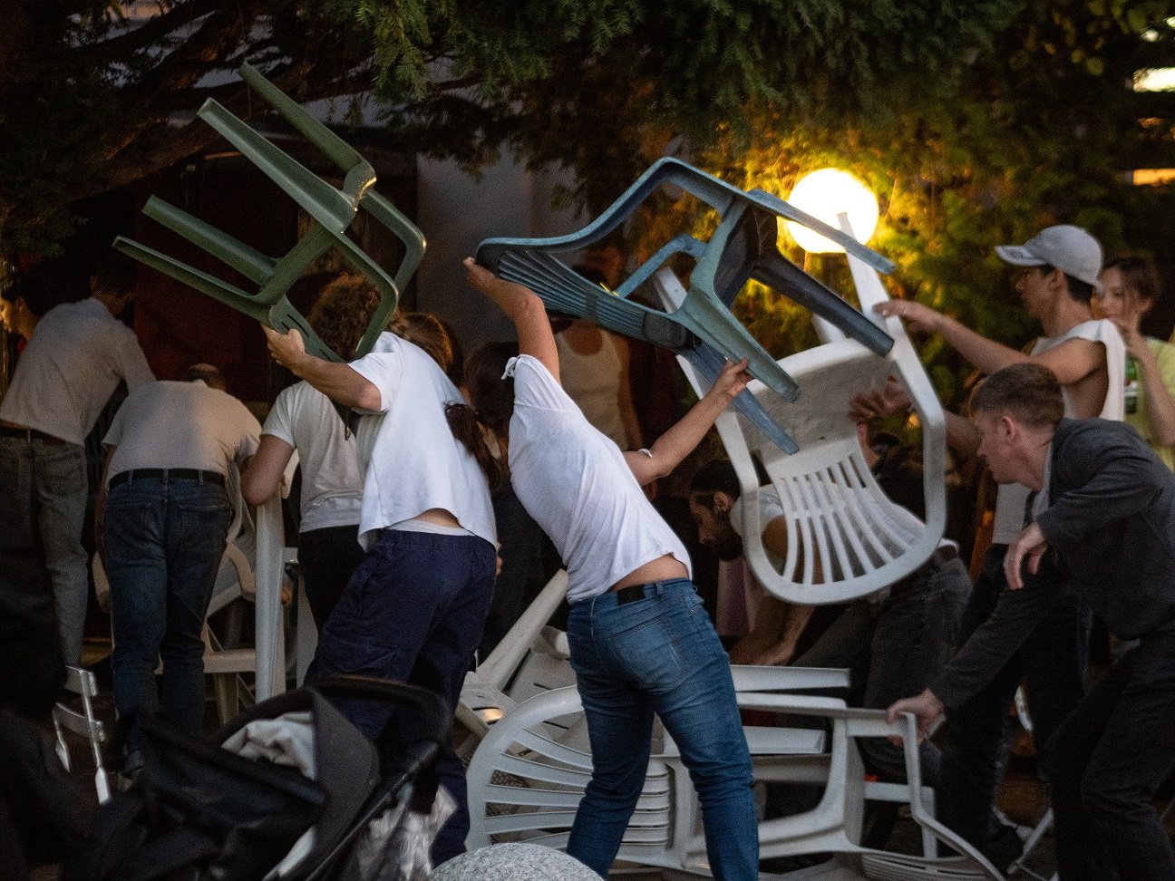 Junge Menschen tanzen mit Plastikstühlen.