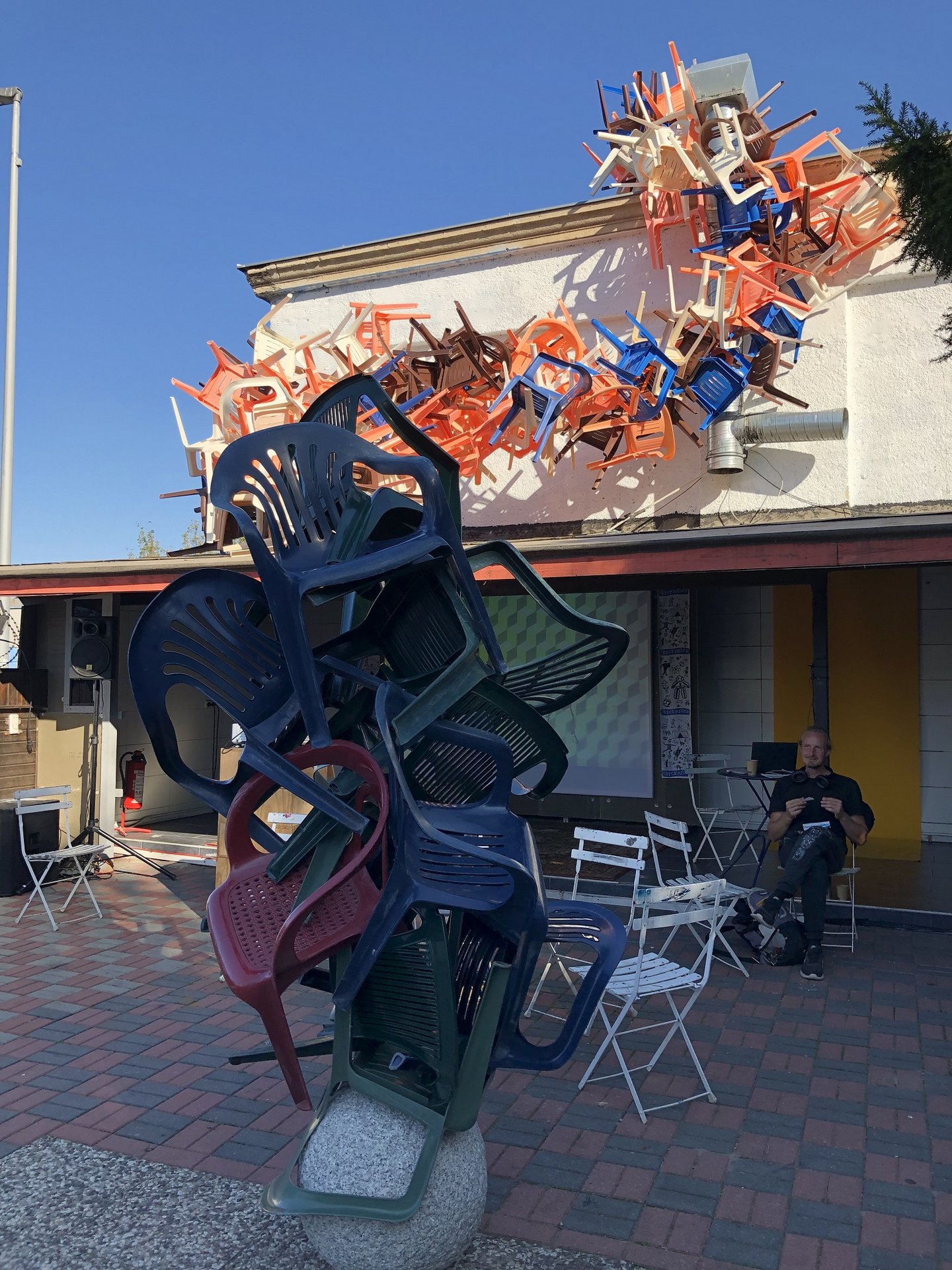 Ein Stapel Plastikstühle, der über ein Hausdach ragt.