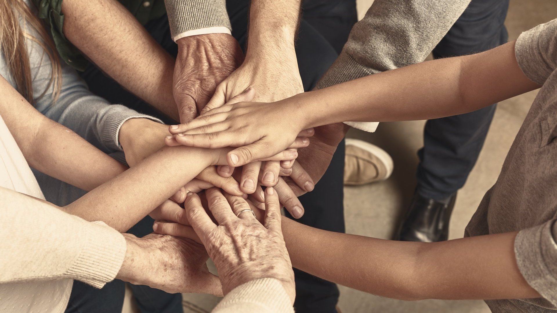 Viele übereinander liegende Hände von Menschen, die in einem Kreis stehen.