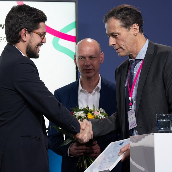 Dr. Michael Harms gratuliert Fundamental Academic Values Award-Drittplatziertem Fernando Romani Sales.