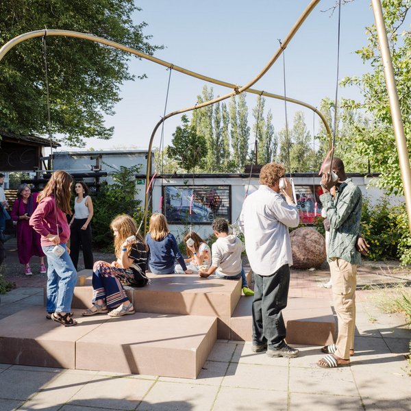 Besuchende hören sich Interviews über kleine, herabhängende Lautsprecher an.