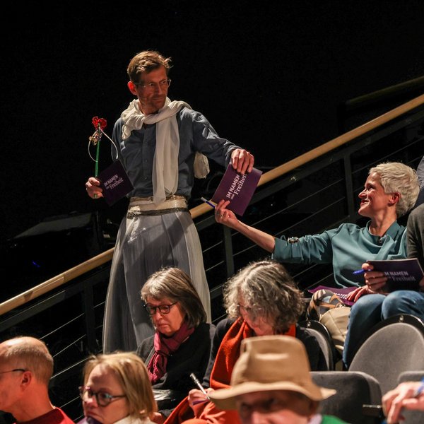 Uwe Gössel als Fee verkleidet verteilt Karten im Publikum.