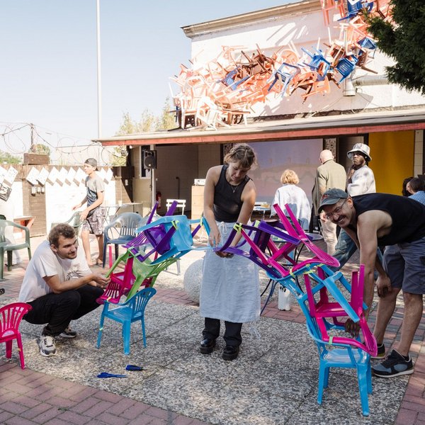 Eine Gruppe Erwachsener baut das Fundament für einen Turm aus Plastikstühlen.