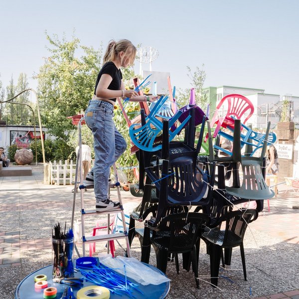 Eine Schülerin baut einen Turm aus Plastikstühlen.
