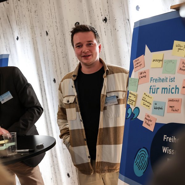 Ein Student der Bürger-Uni Düsseldorf steht neben einer Tafel mit Notizen zu Freiheit.