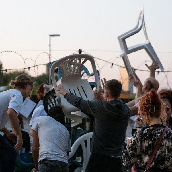 Junge Menschen tanzen mit Plastikstühlen.