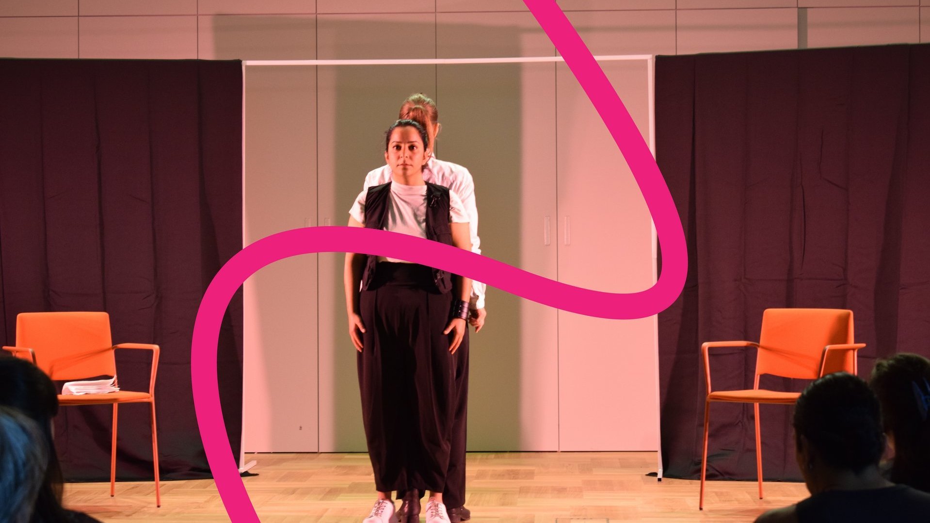 Schauspielende auf einer Bühne, davor die rosa Linie.