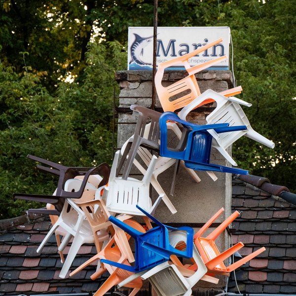 Ein Stapel Plastikstühle auf einem Hausdach.
