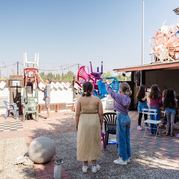 Kinder bauen einen Turm aus Plastikstühlen.