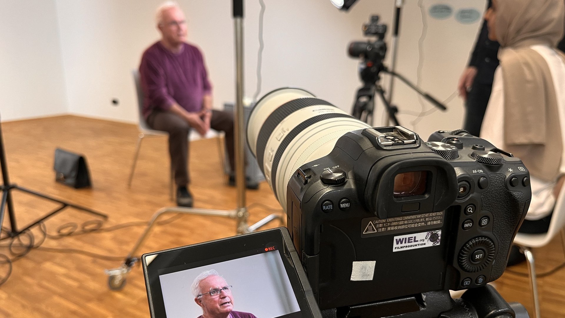 Ein älterer Mann wird interviewt und währenddessen gefilmt.