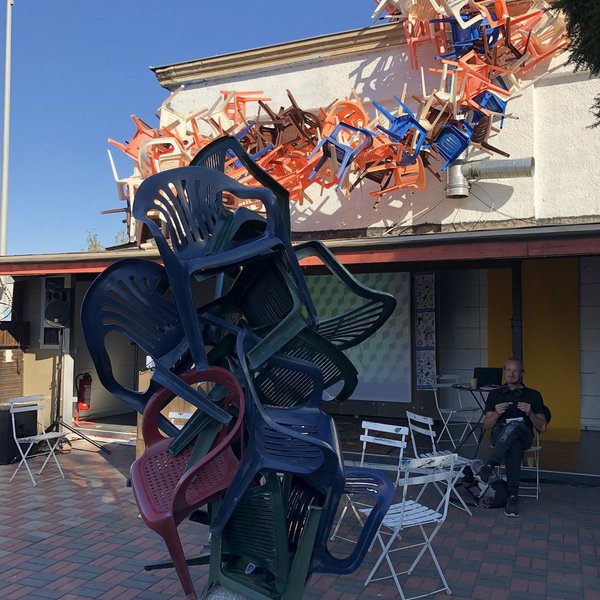 Ein Stapel Plastikstühle, der über ein Hausdach ragt.